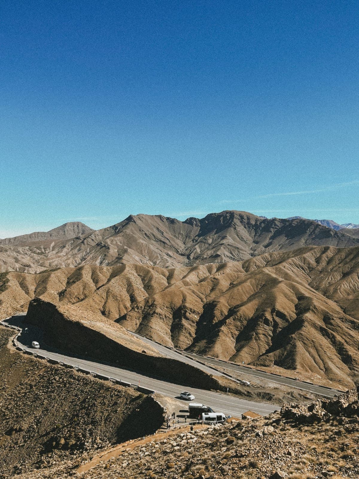 Winding road through the bare Atlas mountains under a blue sky