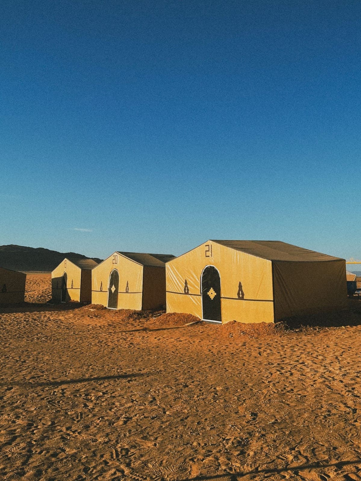 Row of beige tents at a desert camp in the sand