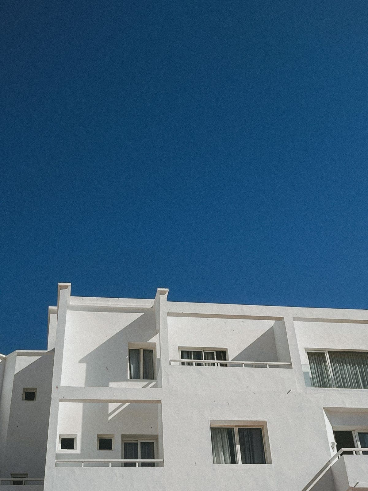 White building with balconies against a deep blue sky